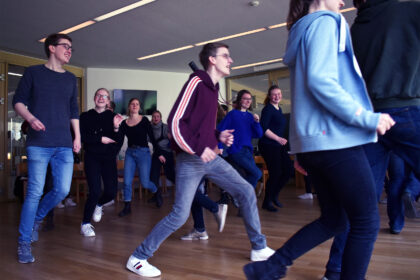 Eine Gruppe junger Menschen läuft im "Hopsa-Lauf" in einem großen Kreis herum.