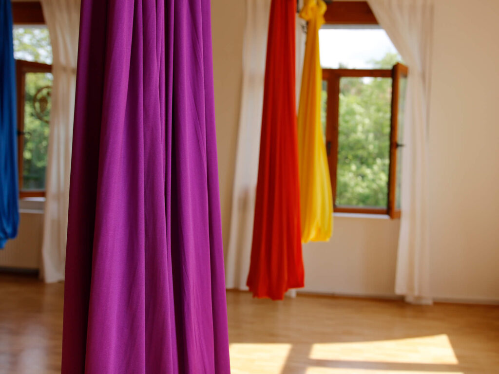 Bunte Aerial Yoga-Tücher hängen von der Decke | Foto: Maarten Hoffmeyer